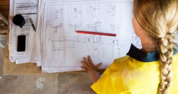 Investissement locatif : et si on aménageait un plateau brut ? Ouvrière qui consulte les plans de construction d'un plateau brut