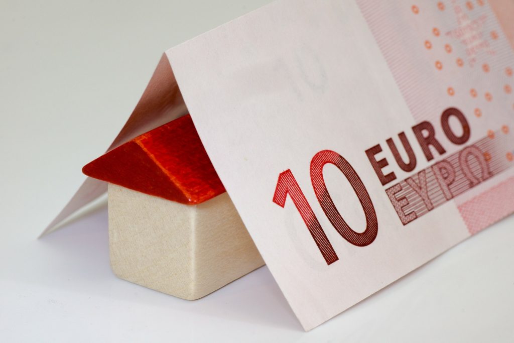 Maison miniature sur laquelle repose des billets en euros