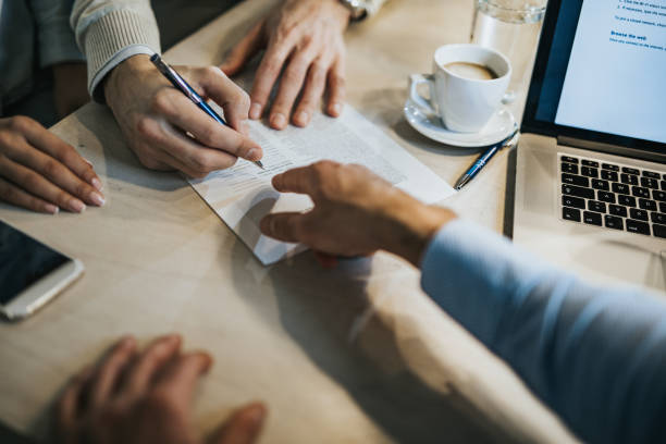 Une personne qui signe un contrat qu'un homme lui tend