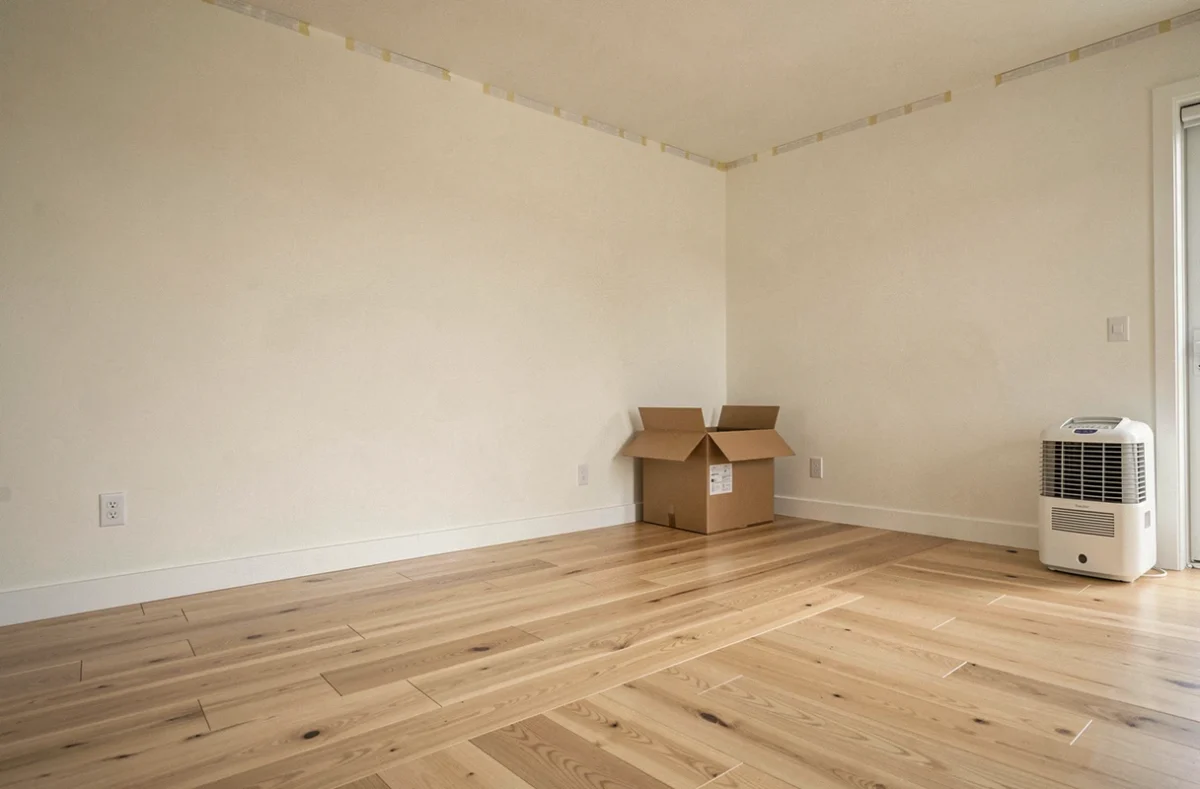 Pièce rénovée après un dégât des eaux avec nouveau parquet et murs repeints en fin de chantier