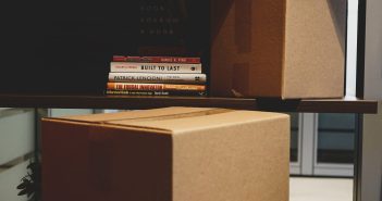 Cartons de déménagement posés sur une table basse et sur une étagère de livres